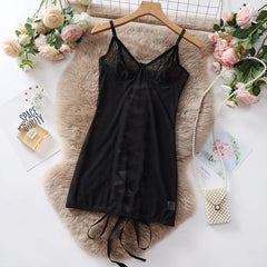 Black slip dress on a hanger with flowers and a bag on a textured surface