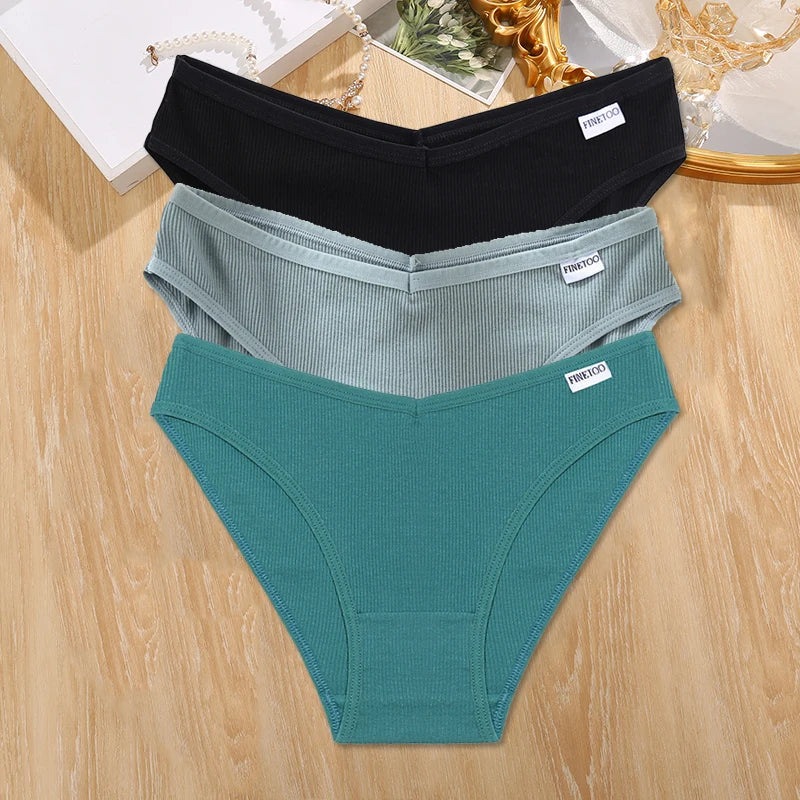 Three pairs of underwear in black, gray, and teal on a wooden surface.