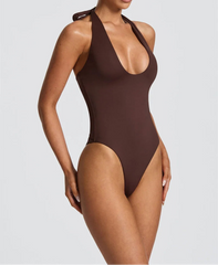 Woman wearing a brown one-piece swimsuit on a plain background