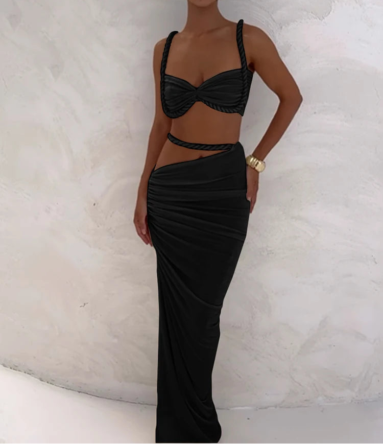 Woman wearing a black bikini and skirt set against a textured white background