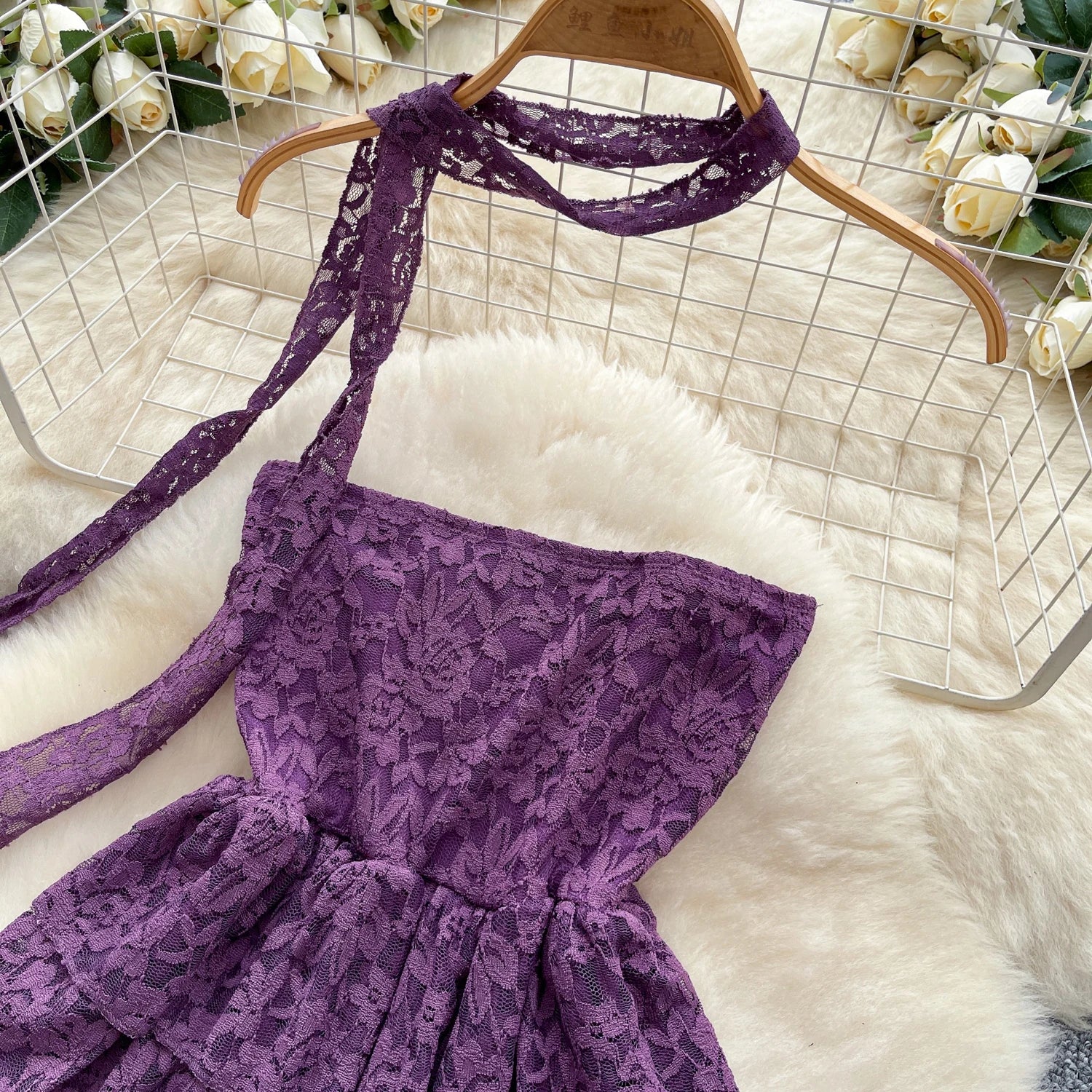 Purple lace dress on a hanger with flowers in the background