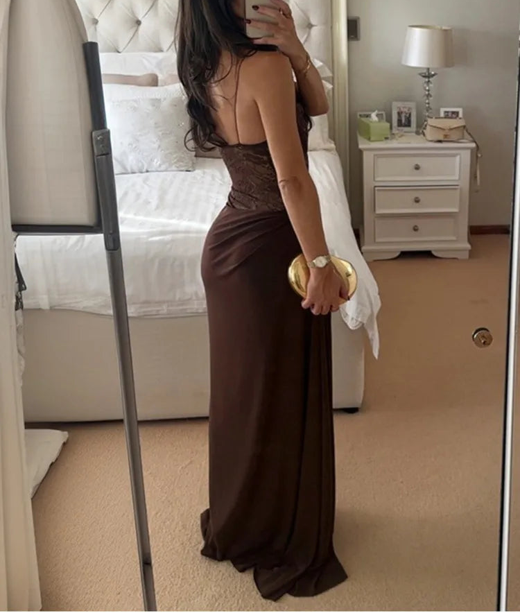 Woman in a brown dress taking a mirror selfie in a bedroom.