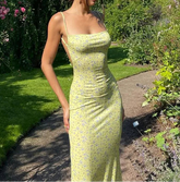 Woman in a yellow floral dress standing in a garden