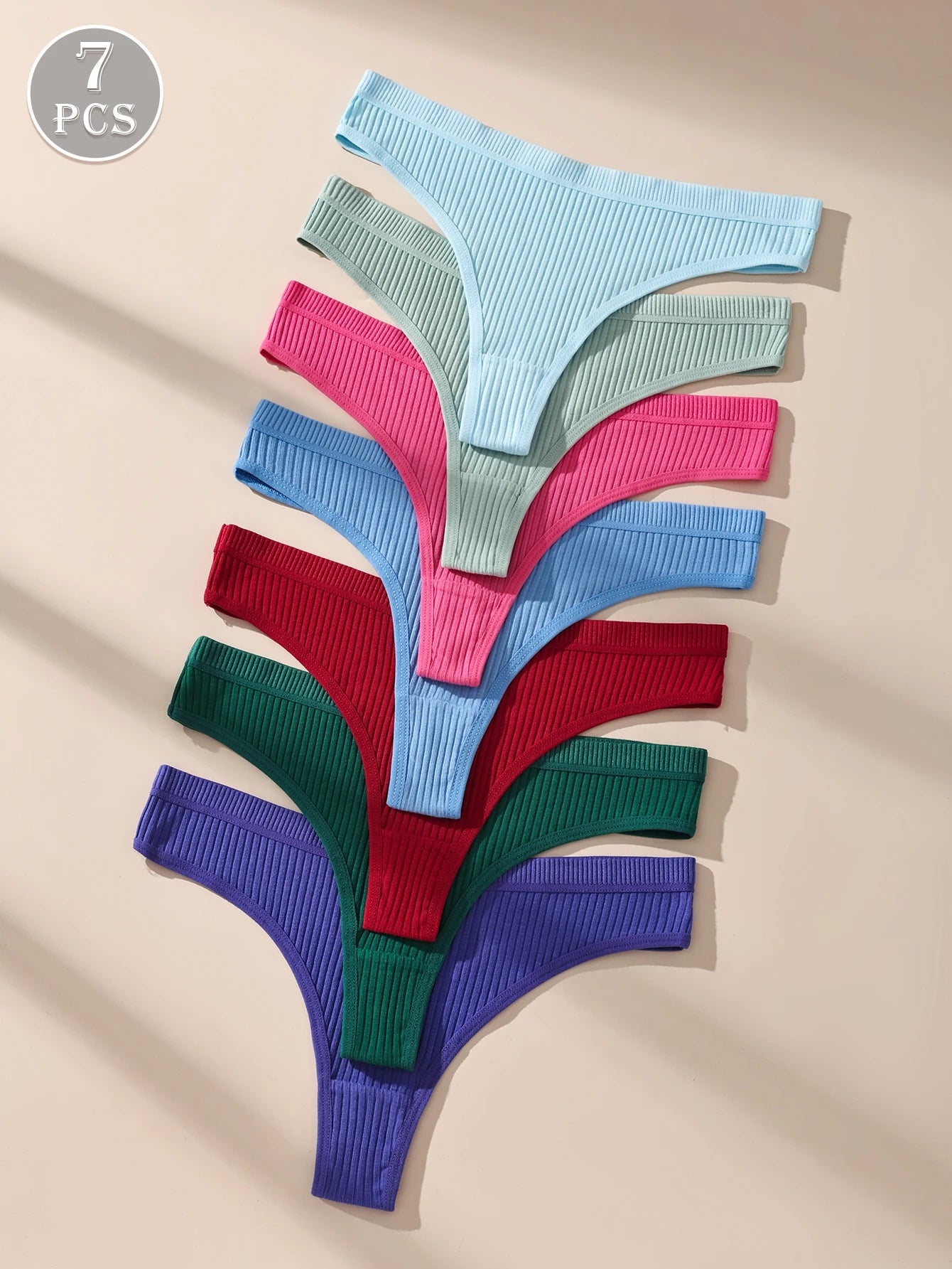 Set of seven colorful knitted thongs on a beige background