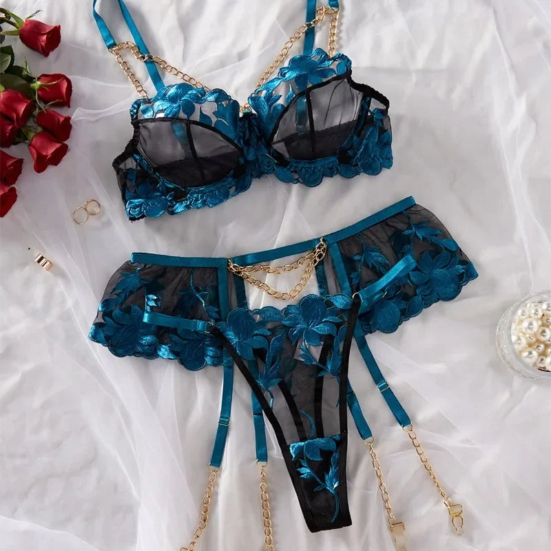 Blue and black floral lingerie set on a white surface with red roses and pearls.