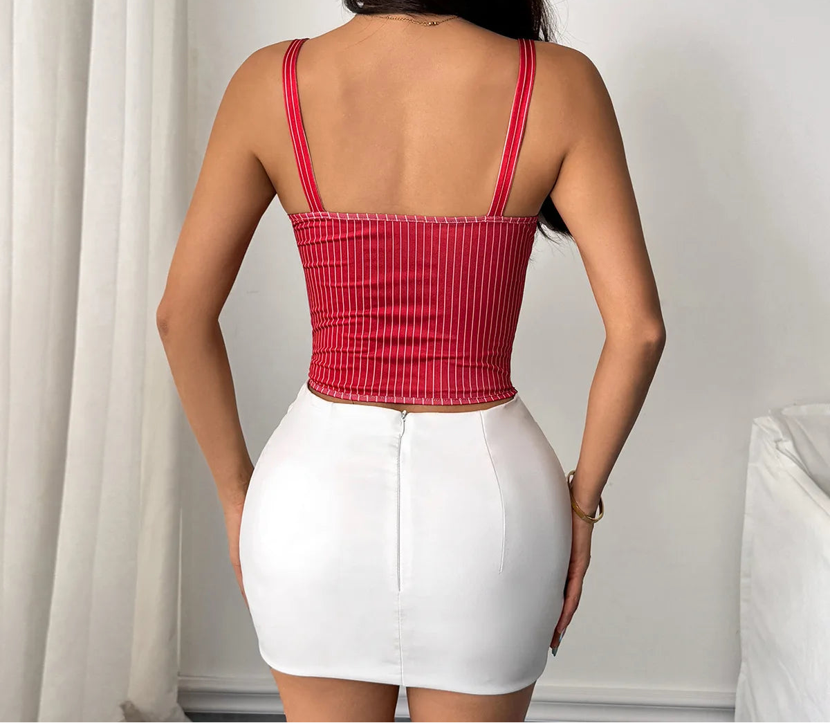 Person wearing a red top and white skirt against a neutral background
