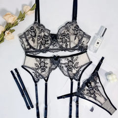 Black lace lingerie set with flowers and a bottle on a white background