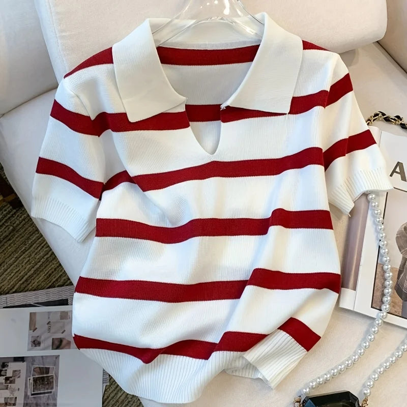 White sweater with red stripes on a hanger against a neutral background
