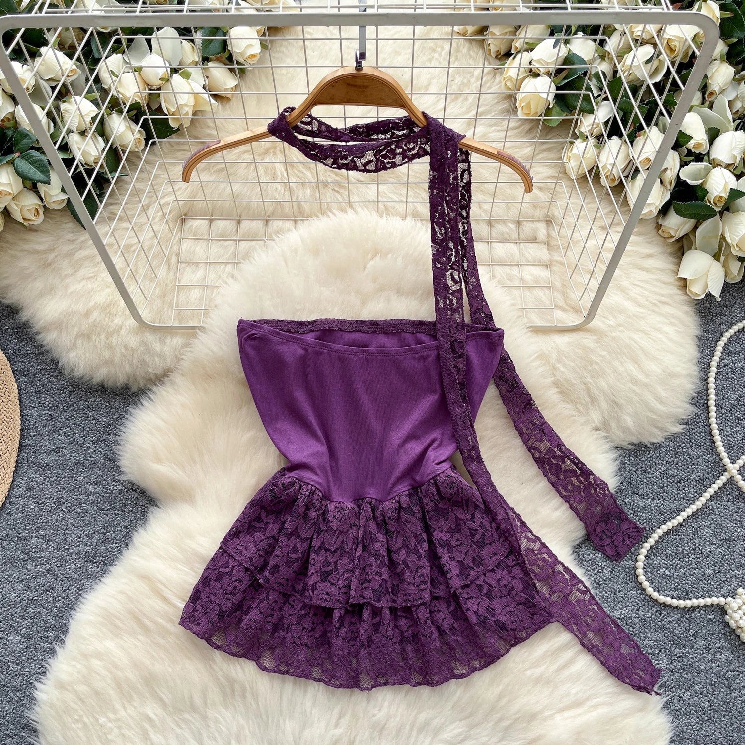 Purple lace dress on a hanger with floral decorations in the background
