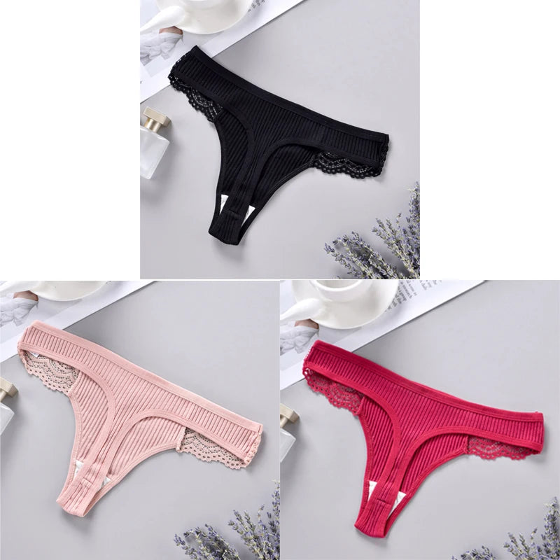 Three pairs of lace-trimmed panties in black, pink, and red on a light gray surface.