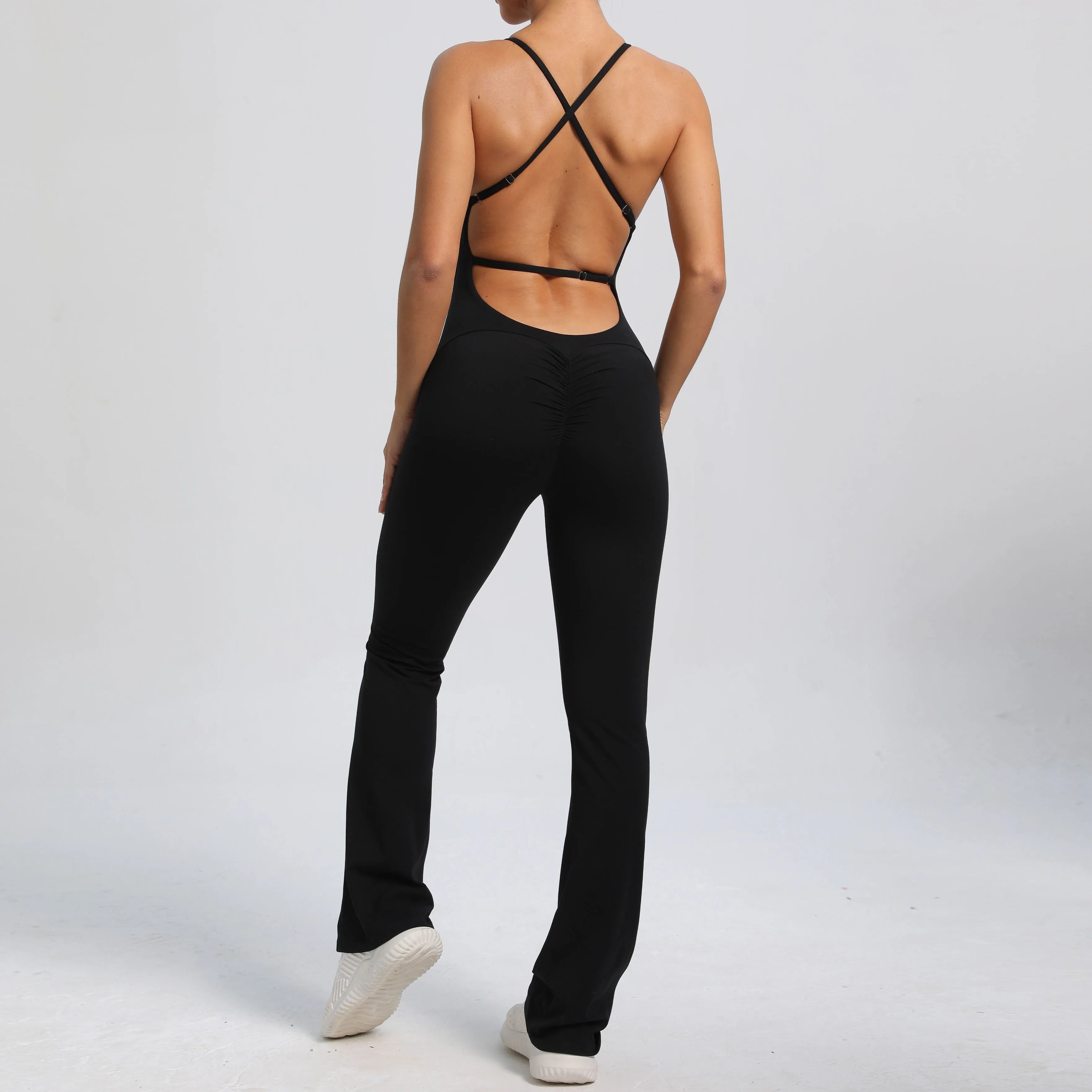 Person wearing a black outfit with open back design on a white background