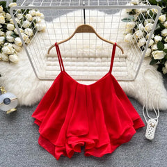 Red spaghetti strap top on a hanger with decorative background
