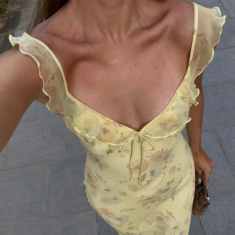 Woman wearing a yellow floral dress with ruffled sleeves on a pavement background