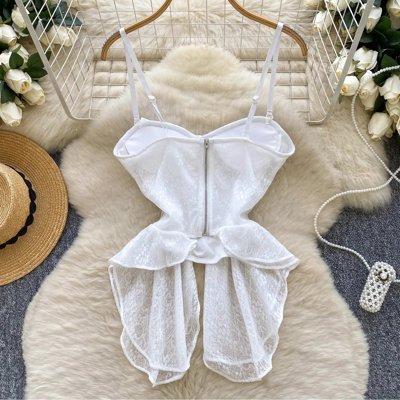 White lace romper on a hanger with decorative elements on a soft surface