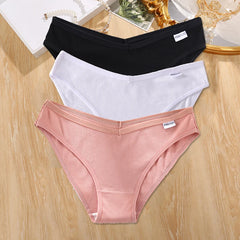 Three pairs of underwear in black, white, and pink on a wooden surface.