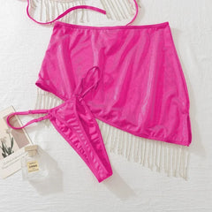 Pink mesh skirt on a white textured surface with a small bottle of perfume.