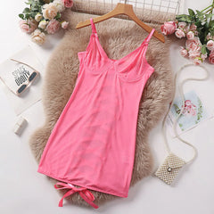 Pink slip dress on a wooden hanger with flowers and a fluffy rug in the background