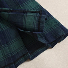 Folded blue and green plaid fabric on a beige surface