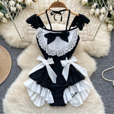 Black and white maid costume with ruffles and bows on a hanger.