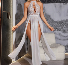 Woman wearing a white lace dress with a high slit in a modern interior setting.