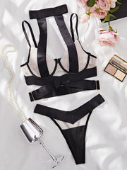 Black lingerie set with a glass of champagne and flowers on a white surface