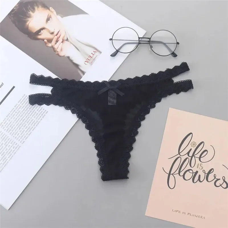 Black lace thong on a gray surface with a magazine, glasses, and a card.