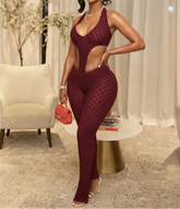 Woman in a burgundy jumpsuit posing in an elegant room.