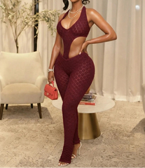 Woman in a burgundy jumpsuit posing in an elegant room.