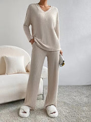 Person wearing a beige ribbed lounge set with matching slippers in a cozy room.