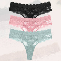 Three pairs of lace underwear in black, pink, and green on a textured background.