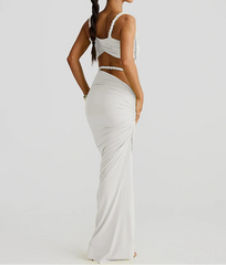 Woman wearing a white evening gown with cut-out design on a plain background