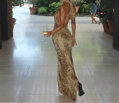 Woman in a leopard print dress holding a glass of wine on a patio.