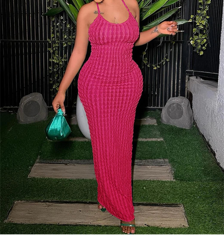 Woman in a pink dress holding a green handbag outdoors.