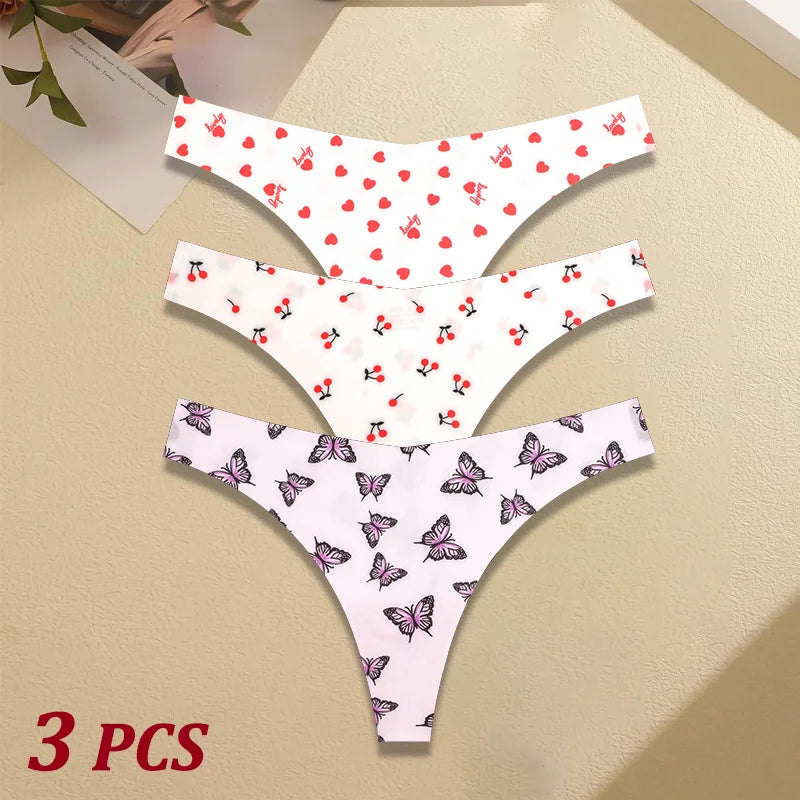Three pairs of women's underwear with cherry and butterfly patterns on a beige surface.