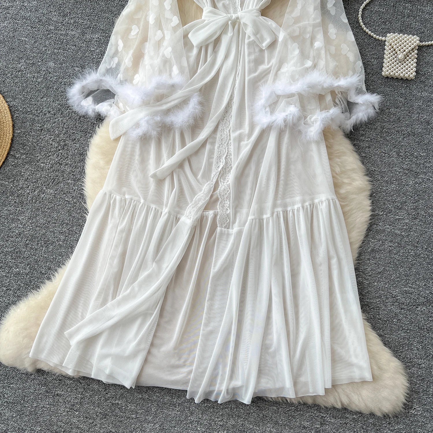 White lace dress with fluffy trim on a textured surface