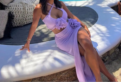 Woman in a lavender outfit sitting by a poolside.
