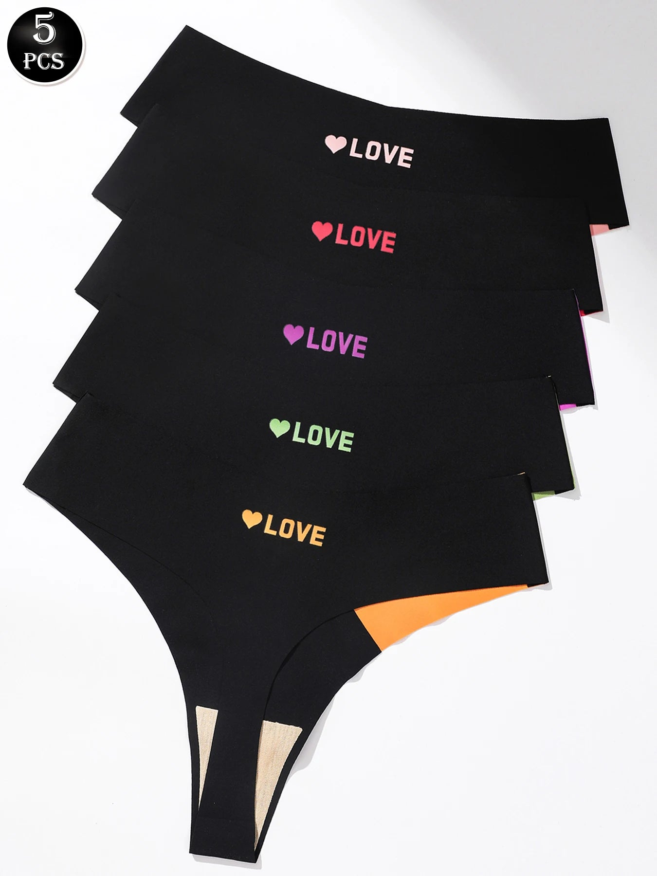 Five pairs of black women's thong underwear stacked diagonally on a white background, each printed with a colorful heart and the word 'LOVE' in different colors (white, pink, purple, green, orange). A black circular badge in the top-left corner reads '5 PCS'.
