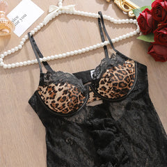 Black lace lingerie with leopard print cups on a wooden surface with jewelry and flowers.