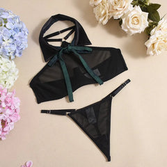 Black lingerie set with green straps on a beige background with flowers.