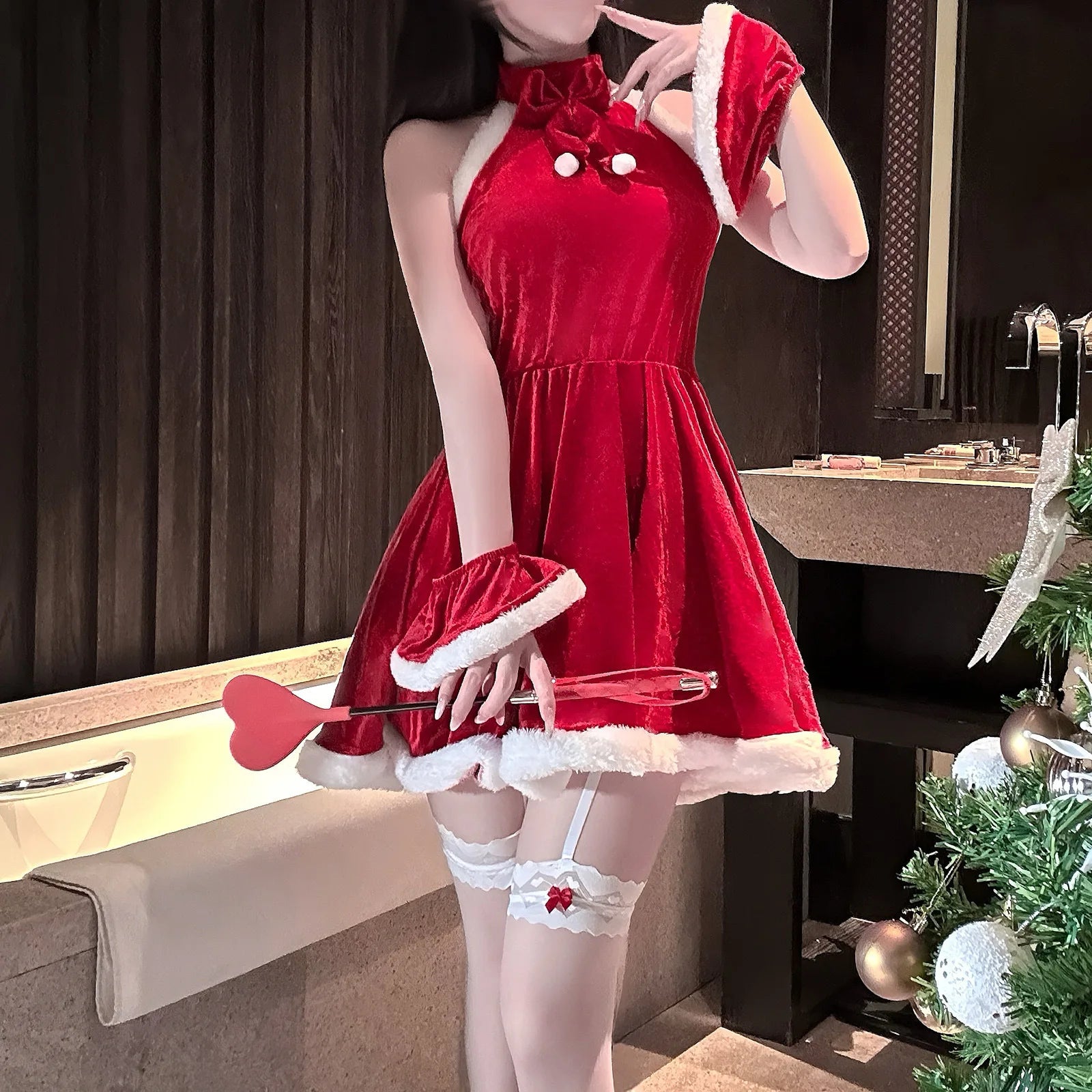 Person wearing a red dress with white accents in a room with a Christmas tree.