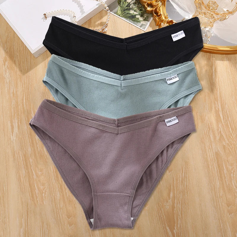 Two pairs of underwear, one black and one gray, on a wooden surface.