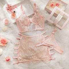 Pink lace lingerie set with flowers and boxes on a textured surface