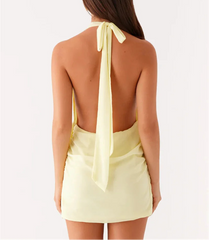 Woman wearing a light yellow halter top with a bow detail on a white background