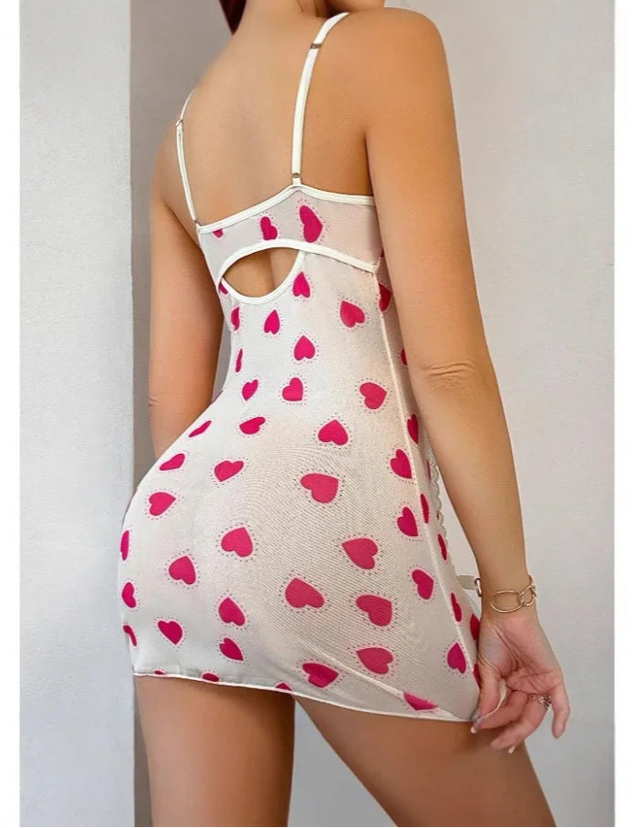 Woman wearing a sheer dress with pink heart patterns on a plain background