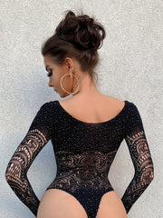 Woman wearing a black lace bodysuit against a textured gray background