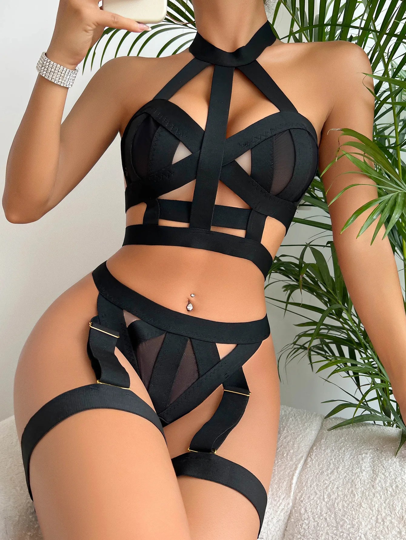 Person wearing a black strappy outfit with a plant in the background