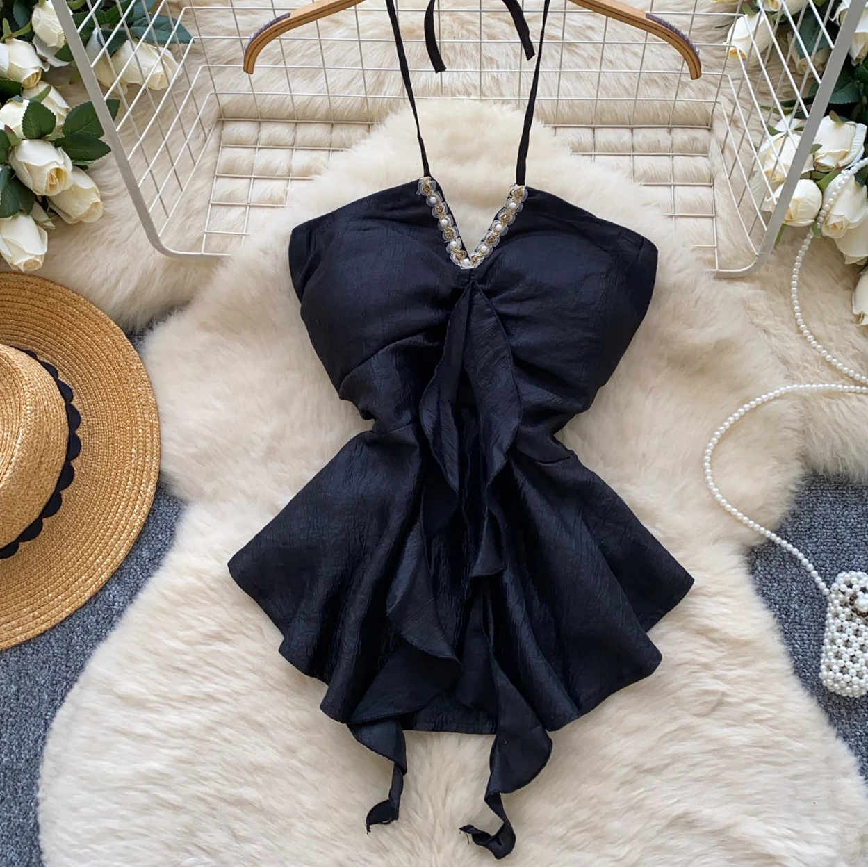 Black dress with a bow on a white fur surface, surrounded by decorative elements.
