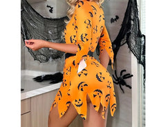 Woman wearing an orange Halloween-themed dress with black patterns in a decorated room.