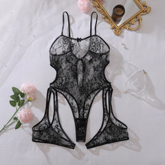 Black lace lingerie set on a white surface with flowers and a mirror.