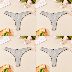 Gray thong with black bows on a beige surface with flowers and stationery.